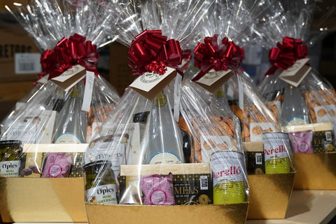 A row of G.J. Andrews holiday gift baskets wrapped in cellophane with red bows and gold baskets