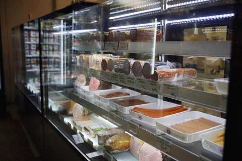 Refrigerated deli case featuring premium meats, sausages, and specialty food products.